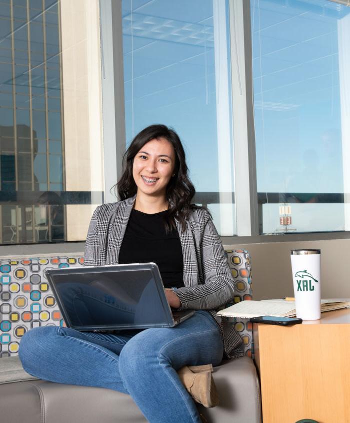 A student sitting on a couch with laptop on her lap.